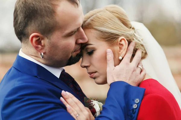 Groom holds bride's face tender kissing her forehead — Stock Photo, Image