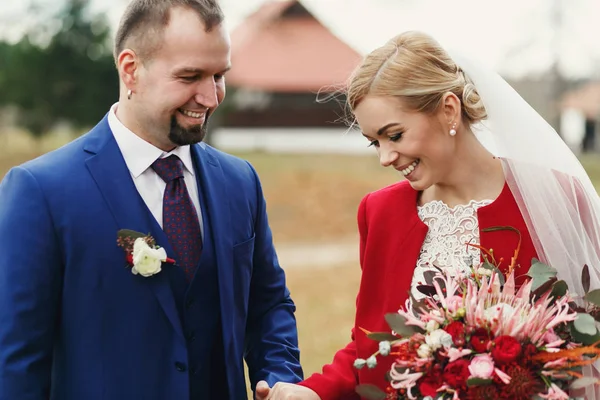 Groom admira uma bela noiva na elegante jaqueta vermelha — Fotografia de Stock
