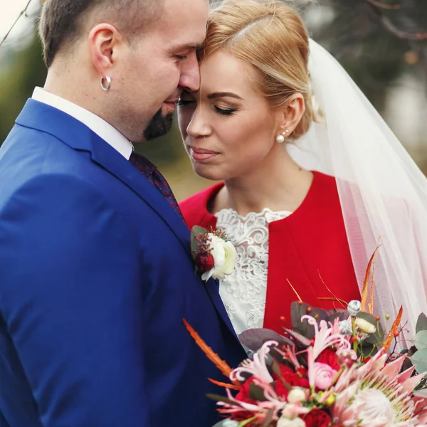 Sposo e sposa si abbracciano con gli occhi chiusi da qualche parte in un parco autunnale — Foto Stock