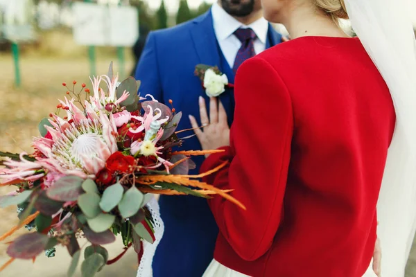 Uma visão de trás em uma noiva em jaqueta vermelha inclinada para um noivo w — Fotografia de Stock