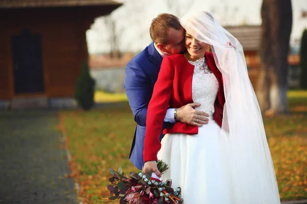 Groom hugs bride from behind and kisses her neck making her smil — Stock Photo, Image