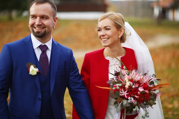 Bello sposo con orecchini sorride mentre cammina con una b bionda — Foto Stock