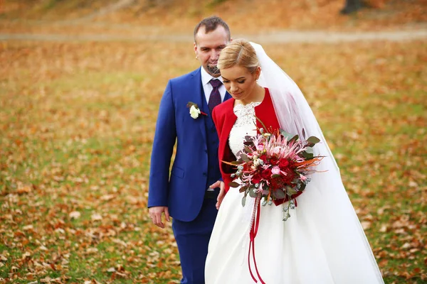 Наречена в червоній куртці з великим весільним букетом гуляє навколо — стокове фото