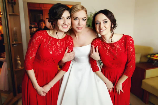 Menyasszony piros öltözött csinos koszorúslányok kezében tartja — Stock Fotó