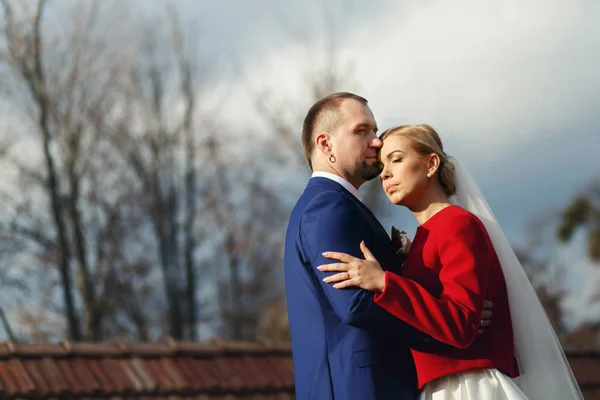 Mariée se penche vers un beau marié debout dans le parc froid d'automne — Photo