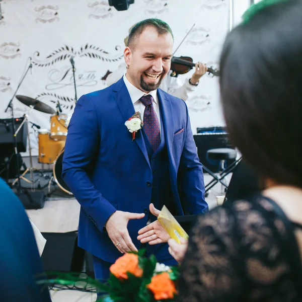 Bräutigam im blauen Anzug erhält Geschenke von Gästen — Stockfoto