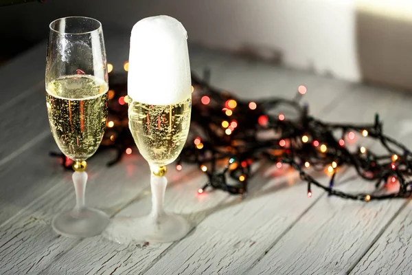 Two glasses of champagne and garland on a white floor — Stock Photo, Image