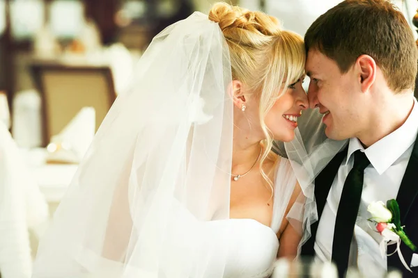 Mariée et marié se touchent le nez assis à la table — Photo