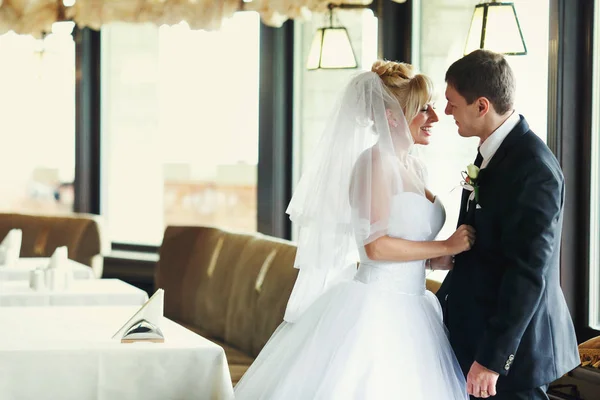 Свадебная пара улыбается, стоя за белыми столиками в ресторане — стоковое фото
