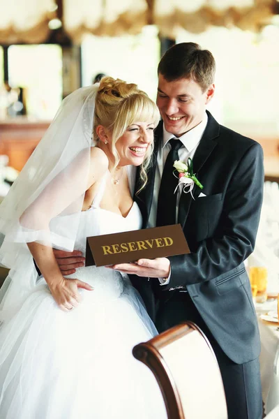 結婚式のカップルが再で「予約済み」のテーブルに立っているを笑 — ストック写真