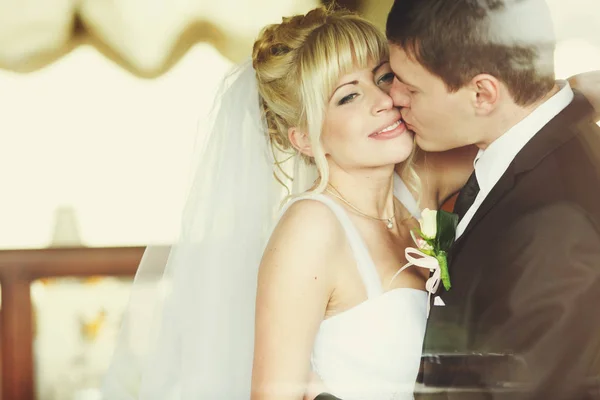 Noivo beija noiva ternamente enquanto ela olha para longe sorrindo — Fotografia de Stock