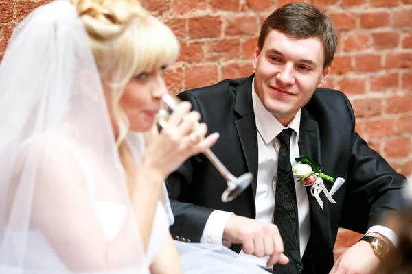 Groom looks at a bride while she drinks champagne — Stock Photo, Image