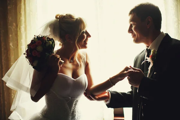 Groom holds arm and elbow of bride's hand standing in the daylig — Stock Photo, Image