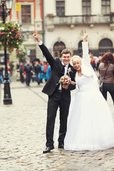 Наречений і наречений піднімають руки вгору в повітрі, показуючи знак — стокове фото