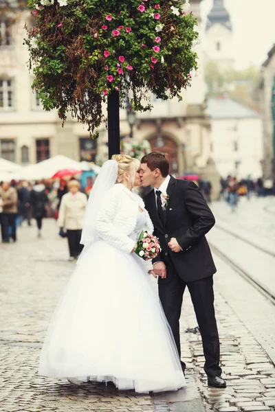 Bara gift par kiss stående på city square — Stockfoto