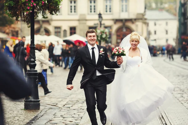 新婚夫妇在城市的某个地方沿着铁路奔跑 — 图库照片