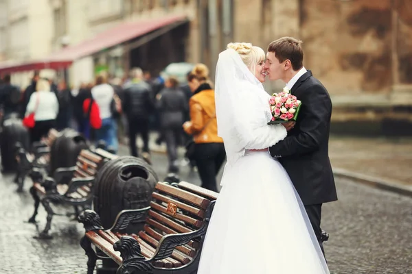 Appena sposati coppia bacio in piedi dietro le panchine sulla stre — Foto Stock