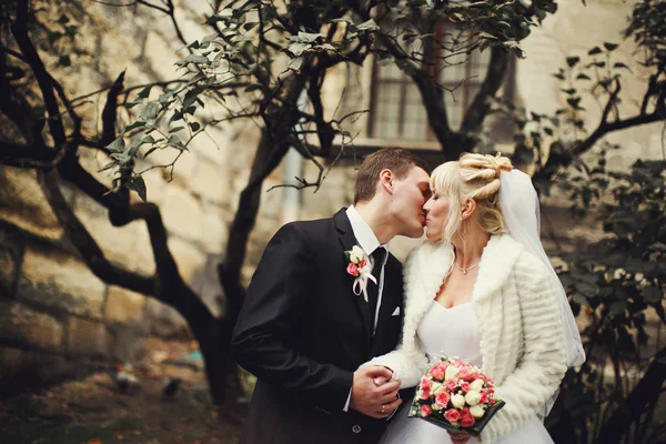 Bride and groom kiss standing in a courtyard — Stock Photo, Image