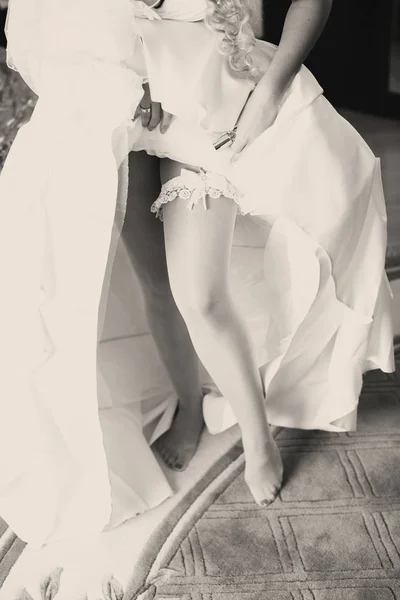 Наречена показує мереживну підв'язку, що піднімається на весільну сукню — стокове фото