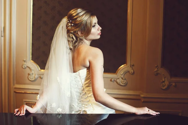 黒のピアノにもたれてゴージャスな金髪の花嫁のプロファイル — ストック写真