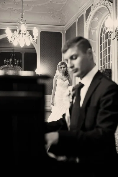 令人惊异的新娘来到弹奏钢琴的新郎 — 图库照片