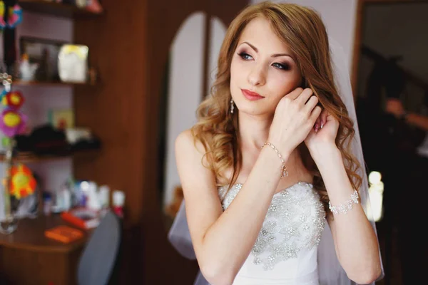 Sposa con splendido make-up regola il suo gioiello in una stanza — Foto Stock