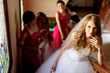 Gelin Küpeşte ayakta iken bridesmai merdivenlerde üzerinde eğilir