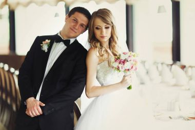 Kafasına bir salonda duran bir gelin ile damat eğilir 