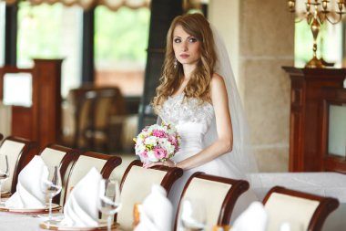 Uzak bir sandalye boş bir restoranda arkasında duran gelin görünüyor 