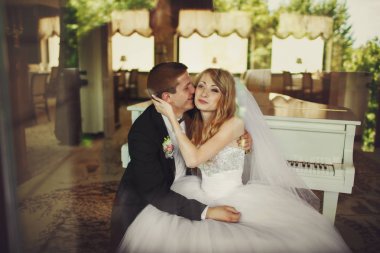 Damat gelinin yanak ve piyano oturan gülümsüyor kisses