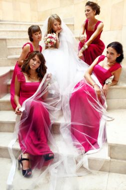 Pembe elbiseler nedime altında oturan bir gelin çevrili