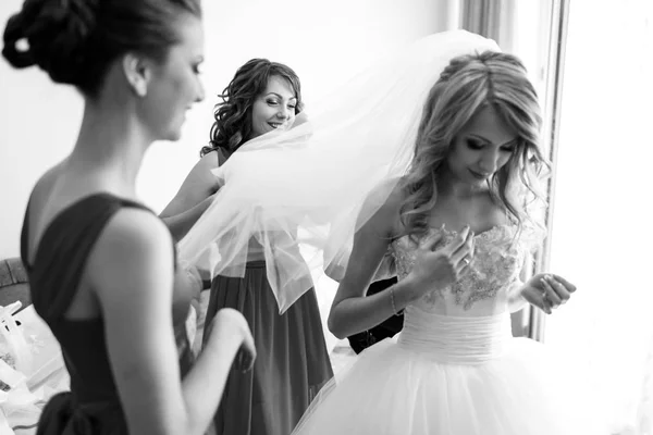 Bruidsmeisjes houdt een sluier terwijl bruid haar korset past — Stockfoto