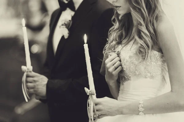 A wedding couple pray holding burning candles in their arms — Stock Photo, Image