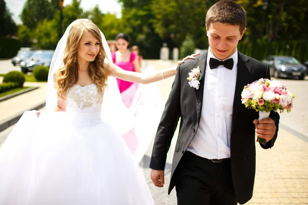 Bride holds groom's shoulder walking with him around the park — Stock Photo, Image