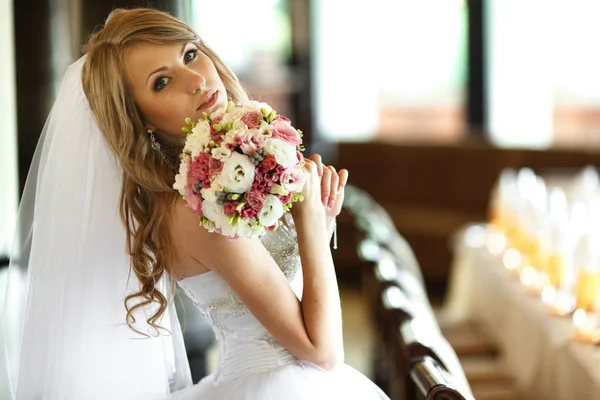 Menyasszony úgy néz ki, lenyűgöző, kezében egy menyasszonyi csokor arca mögött — Stock Fotó