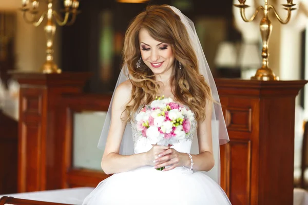 Mooie bruid glimlacht kijken haar boeket — Stockfoto
