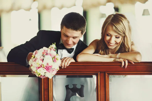 Ein Hochzeitspaar blickt auf ein Geländer gelehnt herab — Stockfoto