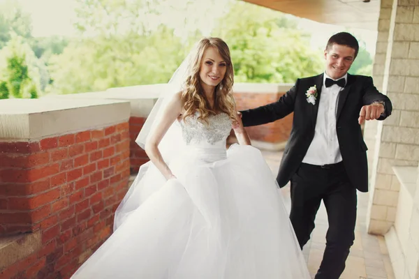 Nevěsta a ženich pěšky podél balkón cihla — Stock fotografie