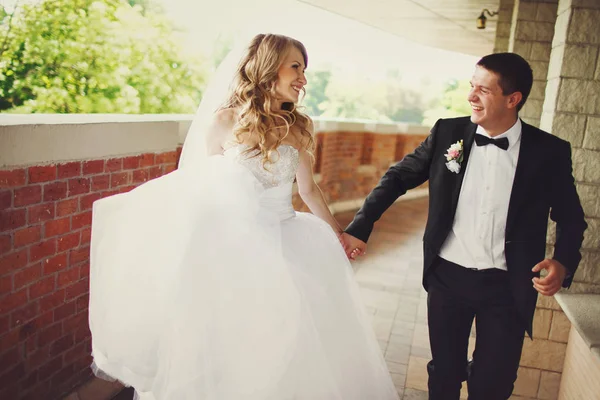 Casamento casal ri enquanto corre ao longo da varanda — Fotografia de Stock