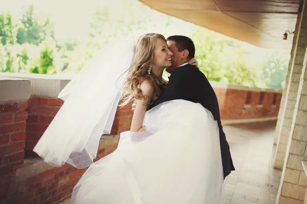 Γαμπρός αγκαλιές Χαμογελαστός νύφη στέκεται στο μπαλκόνι τούβλο — Φωτογραφία Αρχείου