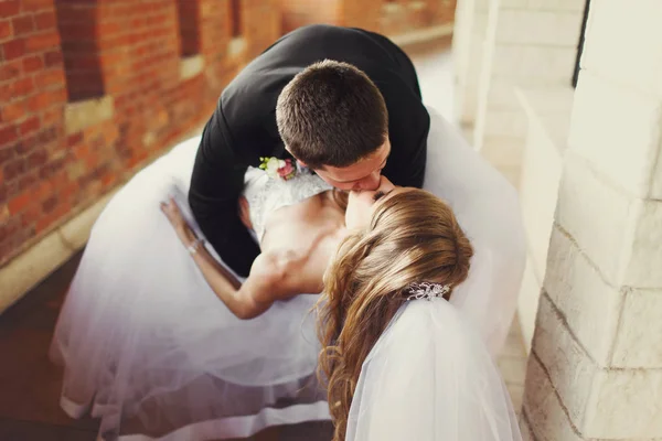 Sposo piega sposa sopra e la bacia in piedi sul balcone — Foto Stock