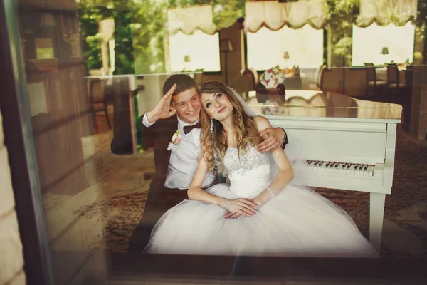 Жених веселится, сидя с невестой за фортепиано — стоковое фото