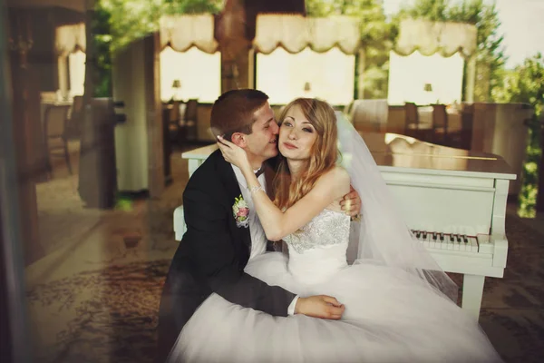 Damat gelinin yanak ve piyano oturan gülümsüyor kisses