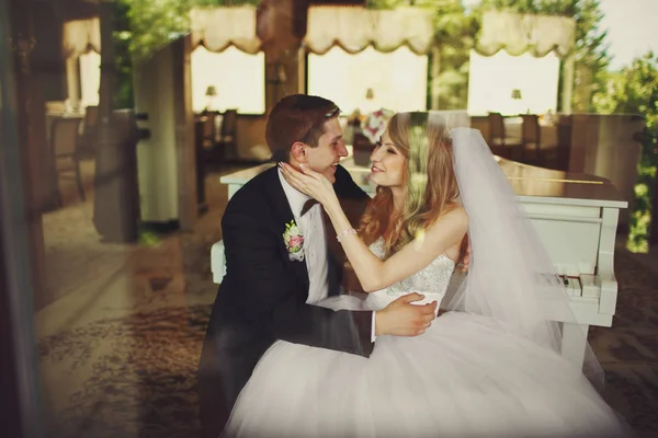 The reflection in window of bride holding groom\'s head tenderly