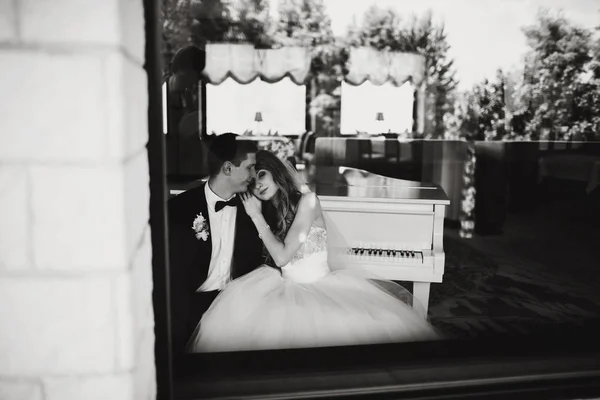 Una vista a través de una ventana en una pareja de boda soñando despierto sentado —  Fotos de Stock