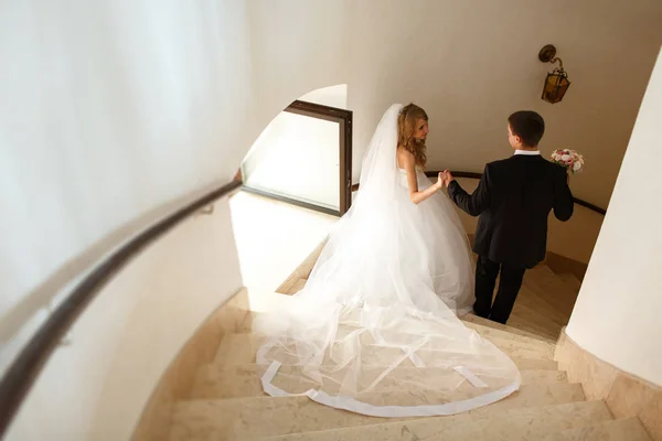 Braut und Bräutigam gehen durch einen Festungseingang die Treppe hinunter — Stockfoto