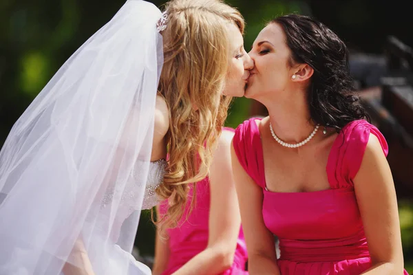 Невеста целует губы подружки невесты в розовом платье — стоковое фото