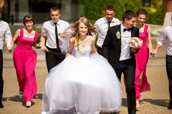 Wind blows bride's hair while she and groom walk in the park sur — Stock Photo, Image
