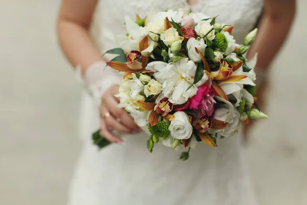 Delicadas manos de novia sostienen un ramo de boda de rosas y verde — Foto de Stock