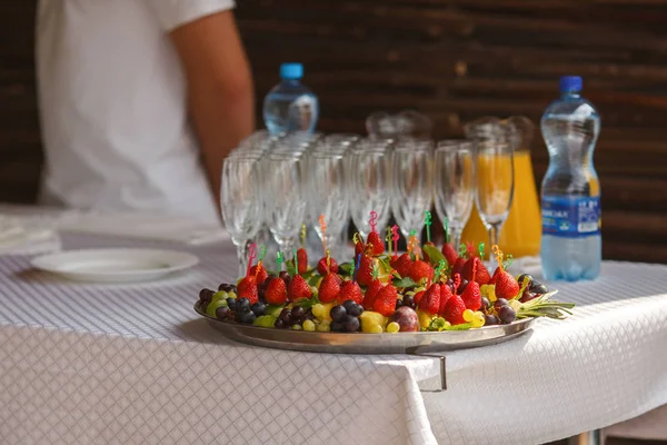 Grapes and strawberries lay on the plate behind empty wineglasse — Stock Photo, Image